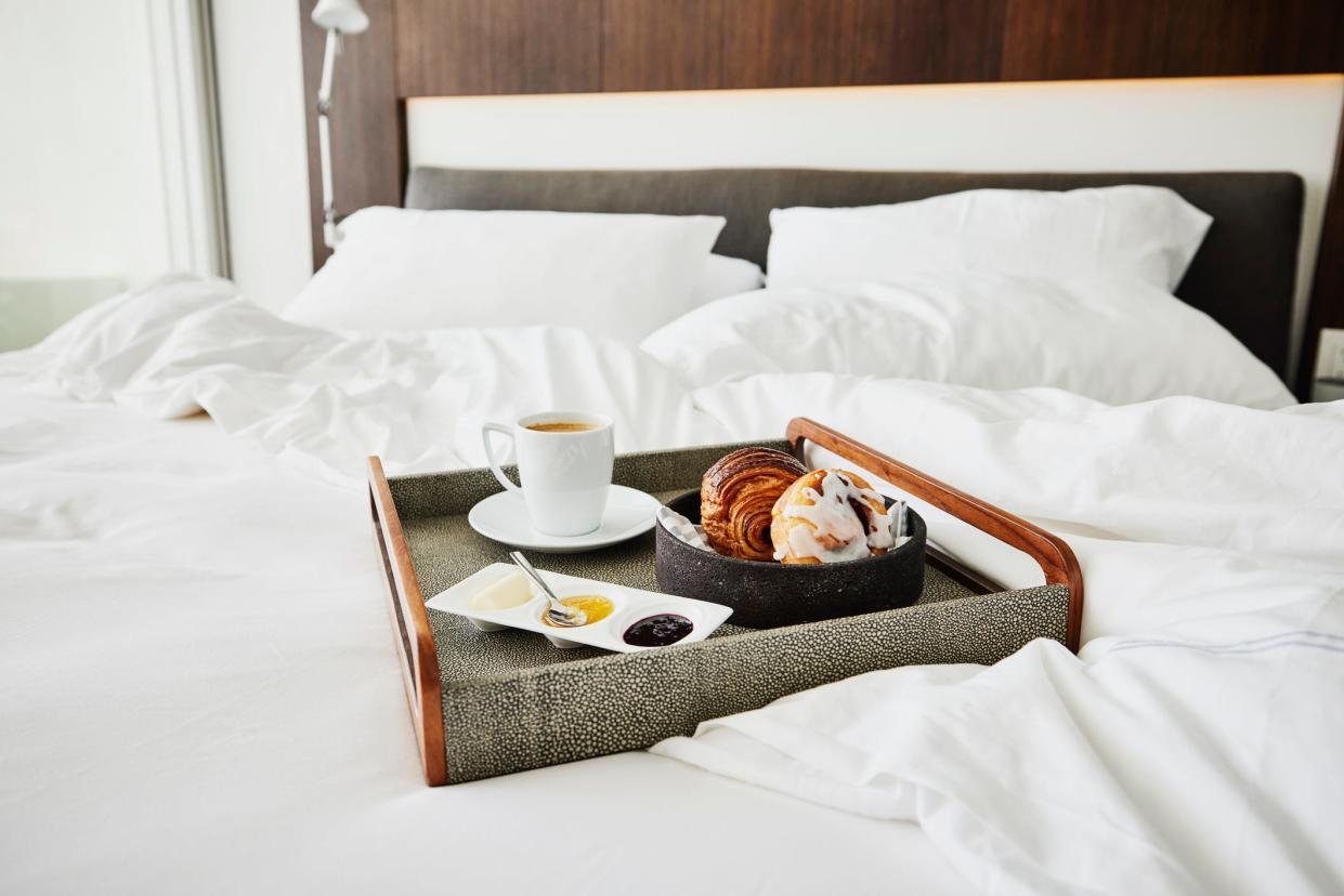 A tray with pastries, jams, and coffee on a hotel bed.