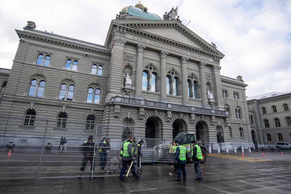 Police officers and logistics personnel set up a protective fence around the Bundesplatz, Government Plaza, in Bern, Switzerland, Sunday, Nov. 28 2021. Swiss voters are having their say in a referendum Sunday on legislation which imposed the use of a special COVID-19 certificate that lets only people who have been vaccinated, recovered, or tested negative attend public events and gatherings. (Peter Schneider/Keystone via AP)