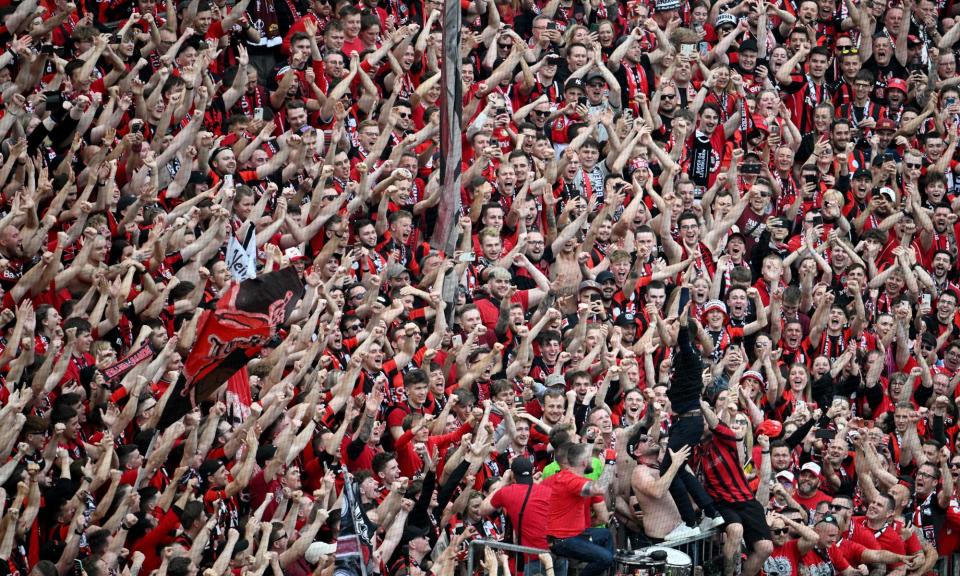 <span>Leverkusen’s Xabi Alonso stands on a barrier as he celebrates with players and fans after winning the Bundesliga.</span><span>Photograph: Sascha Schuermann/AFP/Getty Images</span>