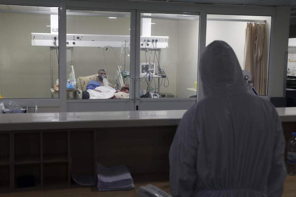 A medical staffer looks at a COVID-19 patient at the intensive care unit of the Rafik Hariri University Hospital in Beirut, Lebanon, Friday, Jan. 22, 2021. Hospitals in Lebanon are reaching full capacity amid a dramatic surge in coronavirus cases across the crisis-hit Mediterranean nation even amid strict lockdown. (AP Photo/Bilal Hussein)