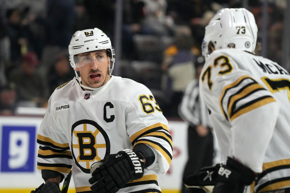 Boston Bruins left wing Brad Marchand (63) talks with Bruins defenseman Charlie McAvoy (73) during the first period of an NHL hockey game against the Arizona Coyotes Tuesday, Jan. 9, 2024, in Tempe, Ariz. (AP Photo/Ross D. Franklin)