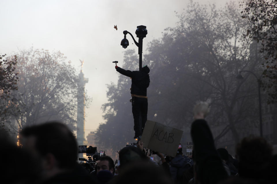 FILE - A protester uses a hammer to break a CCTV camera during a demonstration against a security law that would restrict sharing images of police, Saturday, Nov. 28, 2020 in Paris. A proposed French law for the 2024 Paris Olympics that critics contend will open the door for privacy busting video surveillance technology in France and elsewhere in Europe faces an important hurdle Tuesday March 28, 2023 with lawmakers set to vote on it. The bill would legalize the temporary use of so-called "intelligent" surveillance systems to safeguard the Games and Paralympics. (AP Photo/Francois Mori, File)