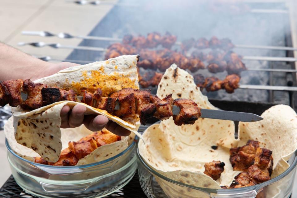 Close-up detail of marinated meats and flatbread on the grill.