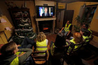 Protesters wearing yellow vests watch French President Emmanuel Macron who addresses the nation about the "yellow vests" crisis on a TV screen in a house in Gaillon, France, December 10, 2018. REUTERS/Philippe Wojazer