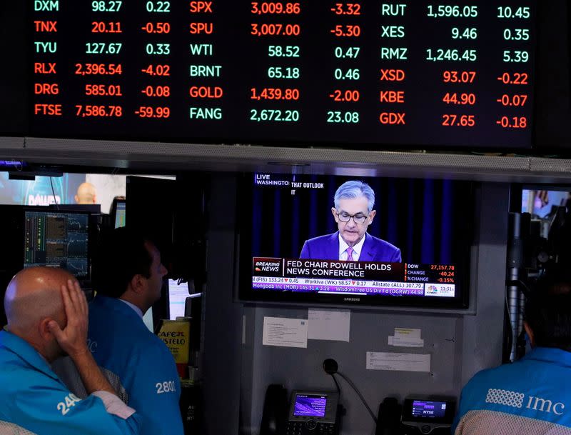 FILE PHOTO: raders look on as a screen shows Federal Reserve Chairman Jerome Powell