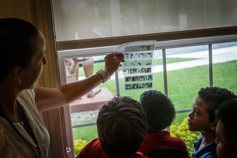 Vanessa Essery, assistant events coordinator, shows a sheet of black-and-white film negatives to West Gate Elementary students during a school trip at the Ann Norton House at the Ann Norton Sculpture Gardens in West Palm Beach on March 6.