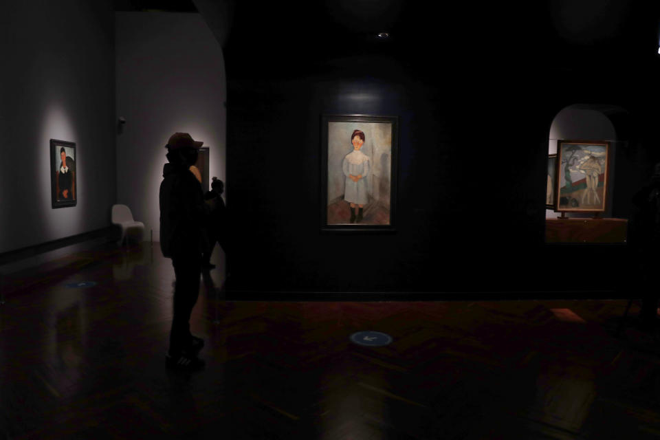 Un periodista observa la pintura “Fillette en bleu” de Amedeo Modigliani en la exposición "El París de Modigliani y sus contemporáneos" en el Museo del Palacio de Bellas Artes en la Ciudad de México el lunes 7 de septiembre de 2020. El museo presenta su primera exposición tras el brote de coronavirus con una gran muestra del pintor italiano. (Foto AP/Marco Ugarte)