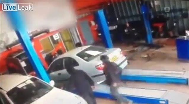 Fellow workers run to the aid of the mechanic after the car launches over the ramp. Photo: Liveleak