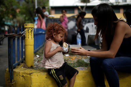 A volunteer of Make The Difference (Haz La Diferencia) charity initiative gives a cup of soup and an arepa to a homeless child in a street of Caracas, Venezuela March 5, 2017. REUTERS/Marco Bello