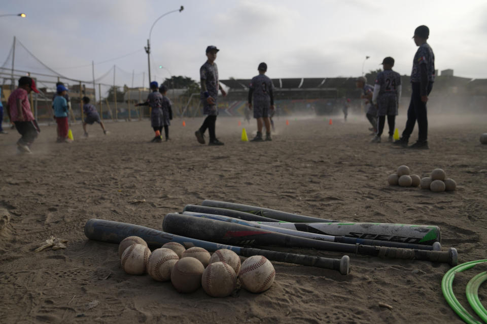 Baseballs and bats lie on a sandy public park, as young Venezuelan migrants practice baseball in the Comas area, on the outskirts of Lima, Peru, Thursday, May 2, 2024. Immigrants, mainly Venezuelans, have opened five baseball academies in Peru's capital. (AP Photo/Martin Mejia)