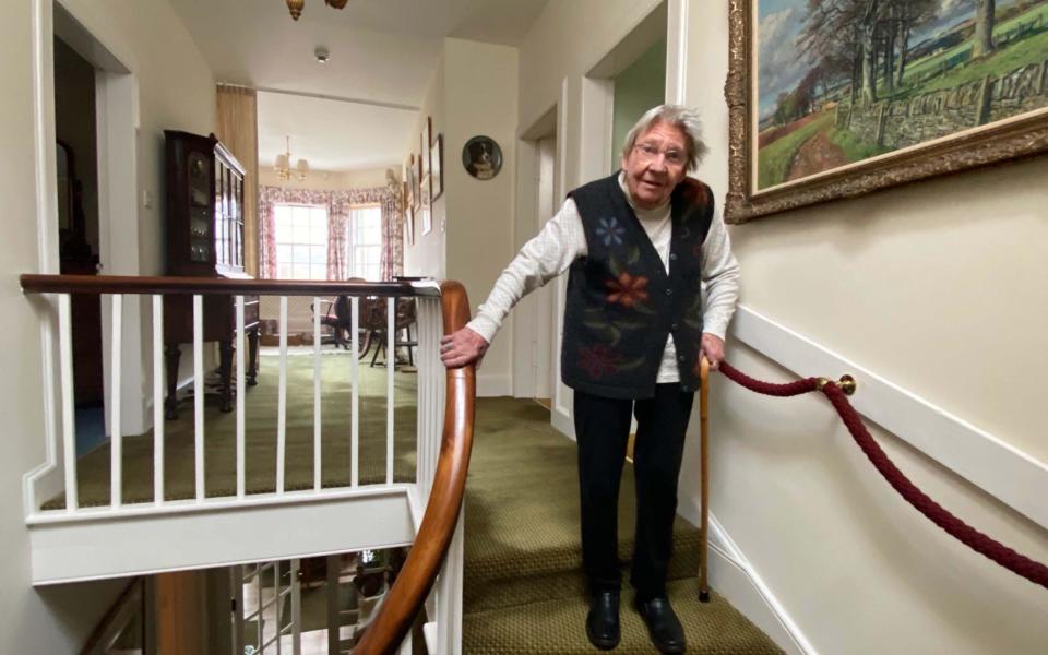 Margaret Payne holding the bannister of the stairs of her home in Ardvar, Sutherland - PA Wire