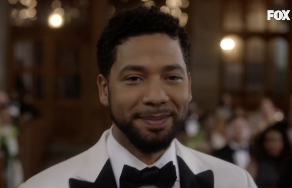 A close up on Jussie Smollett, he's smiling and wearing a white tux with a black bow tie