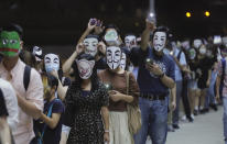Protesters wear masks and hold up their mobile phone lights in Hong Kong, Friday, Oct. 18, 2019. Hong Kong pro-democracy protesters are donning cartoon/superheroes masks as they formed a human chain across the semiautonomous Chinese city, in defiance of a government ban on face coverings. (AP Photo/Kin Cheung)