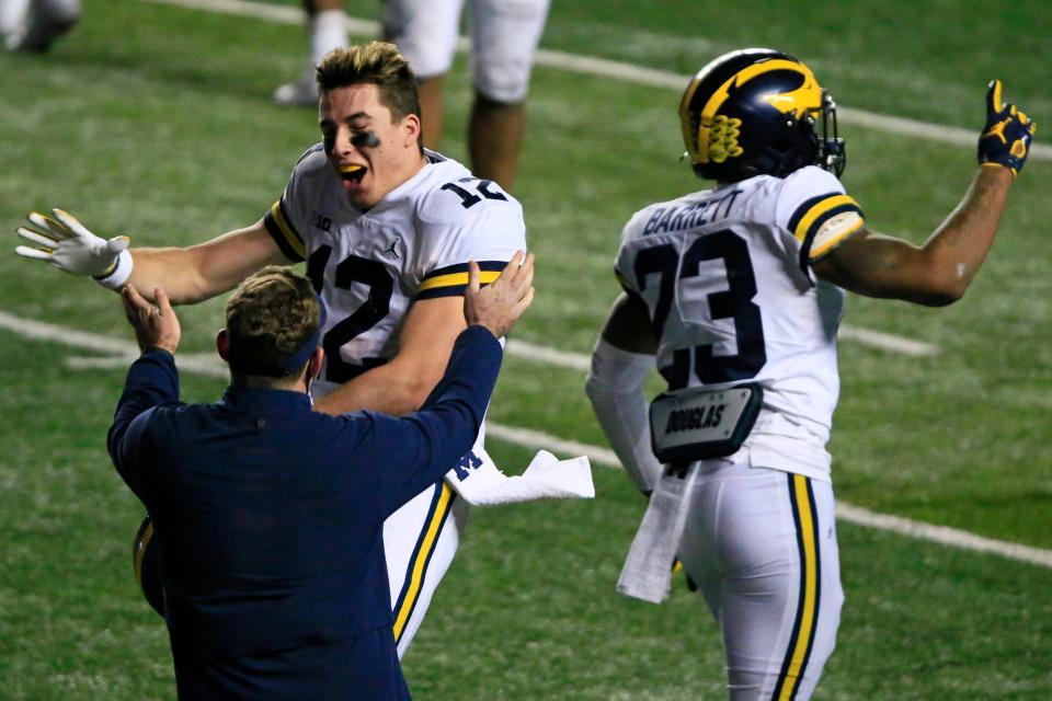 Cade McNamara (12) of the Michigan Wolverines celebrates next to teammate Michael Barrett (23) against the Rutgers Scarlet Knights at SHI Stadium on Nov. 21, 2020 in Piscataway, New Jersey. Michigan defeated Rutgers, 48-42, in triple overtime.