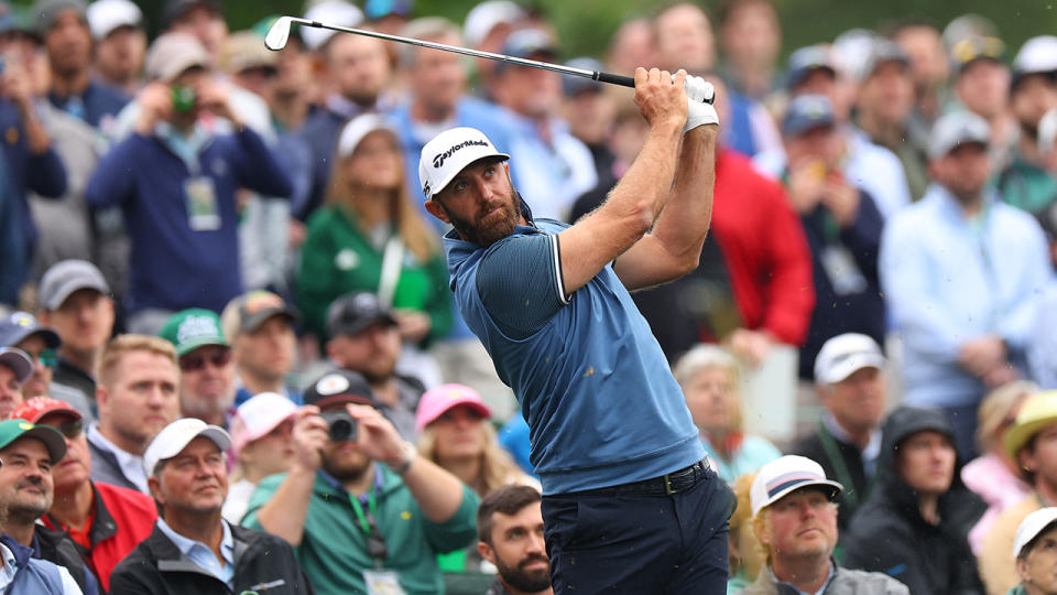 Dustin Johnson plays a shot with a crowd watching on behind.