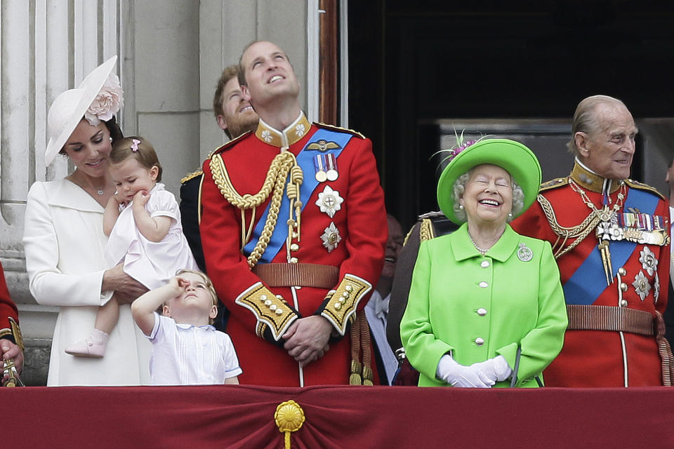 ARCHIVO – La reina Isabel II de Gran Bretaña luce un vestido verde brillante al lado del príncipe Felipe, derecha, el príncipe Guillermo, centro, su hijo el príncipe Jorge, frente, y Catalina, la duquesa de Cambridge quien carga a la princesa Charlotte, izquierda, en el balcón durante el desfile del estandarte en el Palacio de Buckingham en Londres el 11 de junio de 2016. (Foto AP/Tim Ireland, archivo)