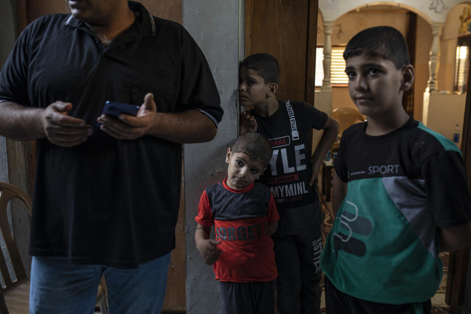 Ibrahim Slaieh's children stand next to their father at their home in Khan Younis, southern Gaza Strip, Wednesday, Aug 17, 2022. Since last year, Israel has issued over 15,000 permits allowing some Palestinians including Slaieh from the Gaza Strip to work in Israel. Their wages are far higher than those available inside Gaza. With Gaza's economy in freefall, these permits are highly coveted and have given an important economic boost to thousands of families. But even Israel acknowledges the system is a powerful tool to preserve calm or — as critics say — control. (AP Photo/Fatima Shbair)