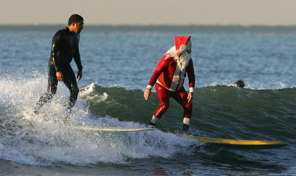 Seal Beach, UNITED STATES:  Michael Pless, dressed in a Santa wetsuit and beard enjoys a Christmas eve surf at Seal Beach, California, early 24 December 2006.  Warm temperatures are forcast for Christmas in southern California.  Pless, a surfing instructor, also has a tuxedo wetsuit for New Years eve.  AFP PHOTO / Robyn BECK  (Photo credit should read ROBYN BECK/AFP via Getty Images)