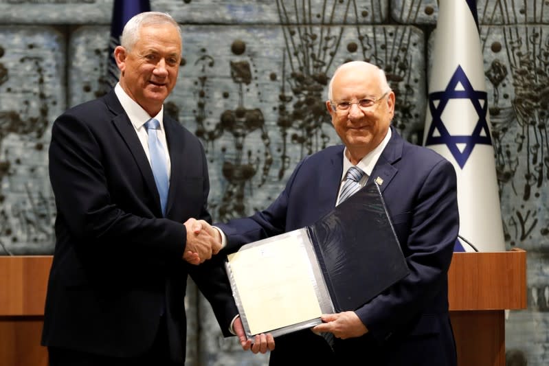 Israeli President Reuven Rivlin gives Benny Gantz, leader of Blue and White party, a file during a nomination ceremony at the President's residency in Jerusalem