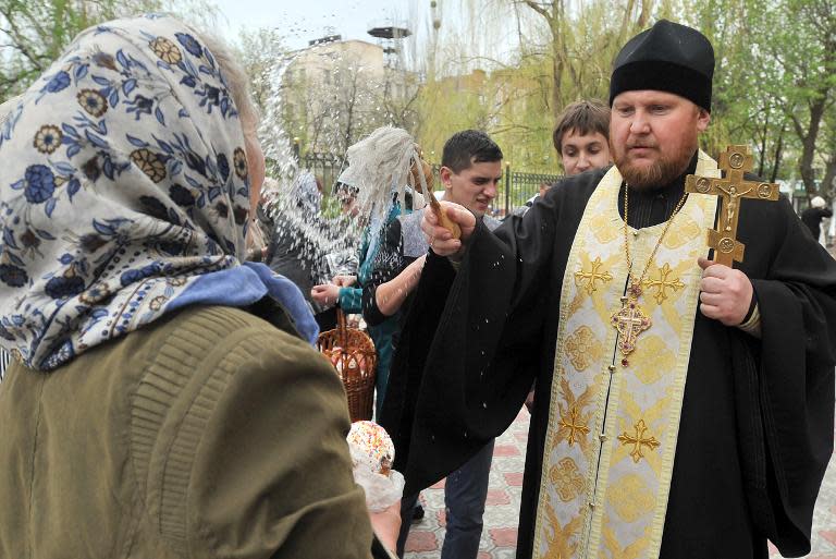 An Orthodox priest blesses the comgregation together with the traditional paschas and eggs they brought during a service outside the cathedral of the eastern Ukrainian city of Slavyansk on April 19, 2014