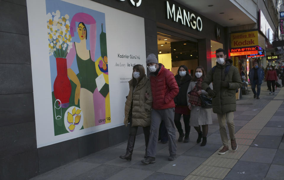 People walk past a poster of a painting by Mexico City-based artist Ana Leovy, by the entrance of a shop, on International Women's Day, in Ankara, Turkey, Monday, March 8, 2021. (AP Photo/Burhan Ozbilici)