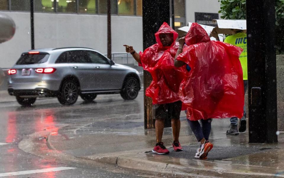 People are seen wearing ponchos as lightning and heavy rain falls over the area on Monday, June 19, 2023, in Miami, Fla.
