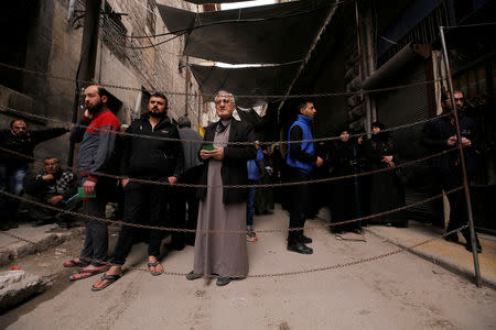 People wait for food aid behind a chain barrier in Aleppo's Kalasa district, Syria April 9, 2019. REUTERS/Omar Sanadiki