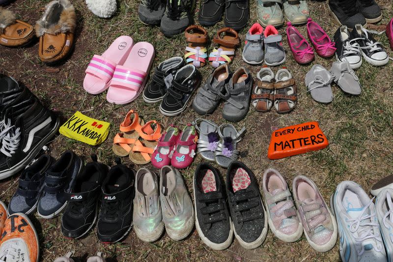 Children's shoes line the base of the defaced statue of Egerton Ryerson in Toronto