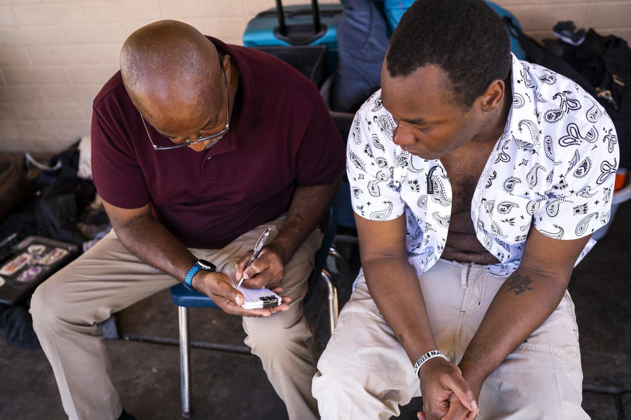 Pastor Cleo Lewis, left, writes down his information for Justin Duckworth, right, at Sunnyslope Dining Room on Thursday, March 24, 2022, in Phoenix. Lewis used to be homeless and now serves as a street minister to people experiencing homelessness.