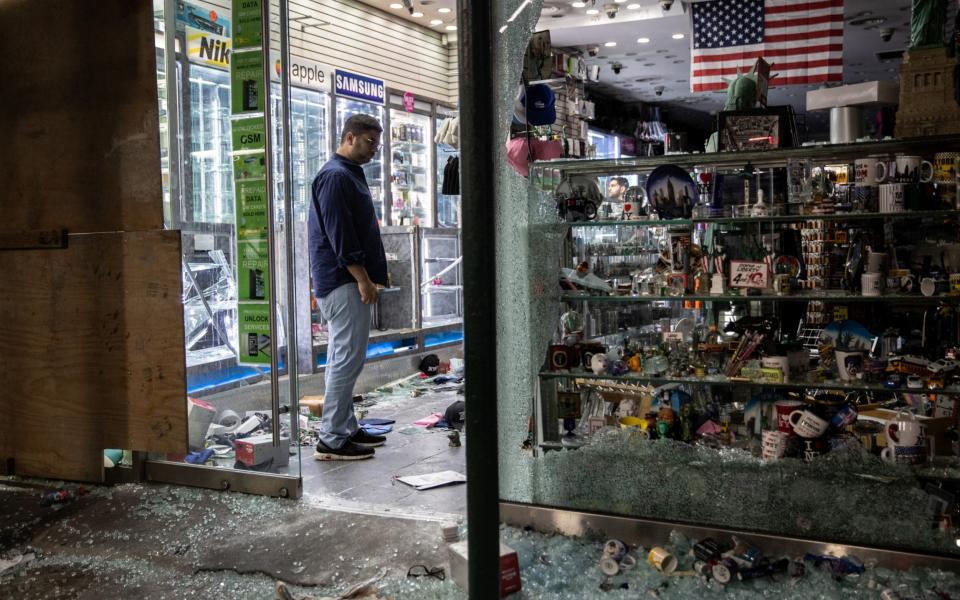  A shop owner looks over damage in a looted souvenir shop near Times Square after a night of protests and vandalism over the death of George Floyd  - Getty