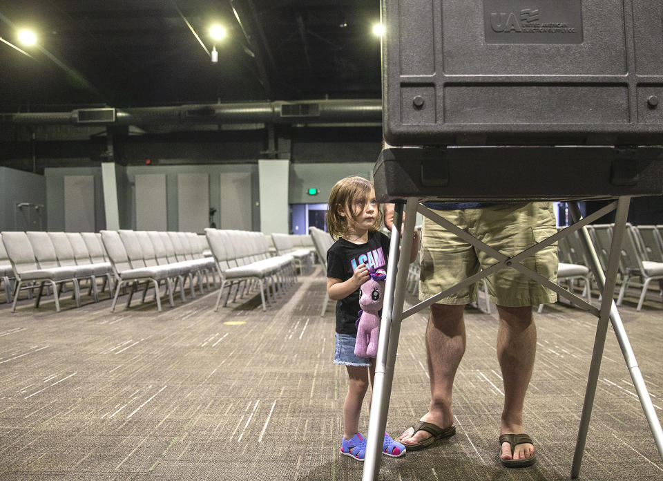 Two-year-old Sophia (no last name given) watches her grandfather Michael Daywalt cast his ballot in the Republican primary at Mount Ararat Church in Stafford County, Va., on Tuesday, June 21, 2022. (Peter Cihelka/The Free Lance-Star via AP)