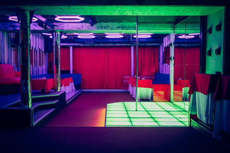 night club interior with pole dance stage with neon lights no people