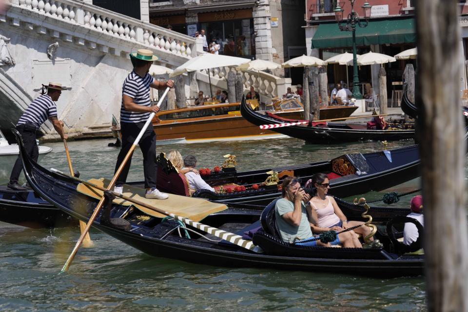 Tourists enjoy a Venetian gondola tour, in Venice, Italy, Thursday, June 17, 2021. After a 15-month pause in mass international travel, Venetians are contemplating how to welcome visitors back to the picture-postcard canals and Byzantine backdrops without suffering the indignities of crowds clogging its narrow alleyways, day-trippers perched on stoops to imbibe a panino and hordes of selfie-takers straining for a spot on the Rialto Bridge or in front of St. Mark’s Basilica. (AP Photo/Luca Bruno)