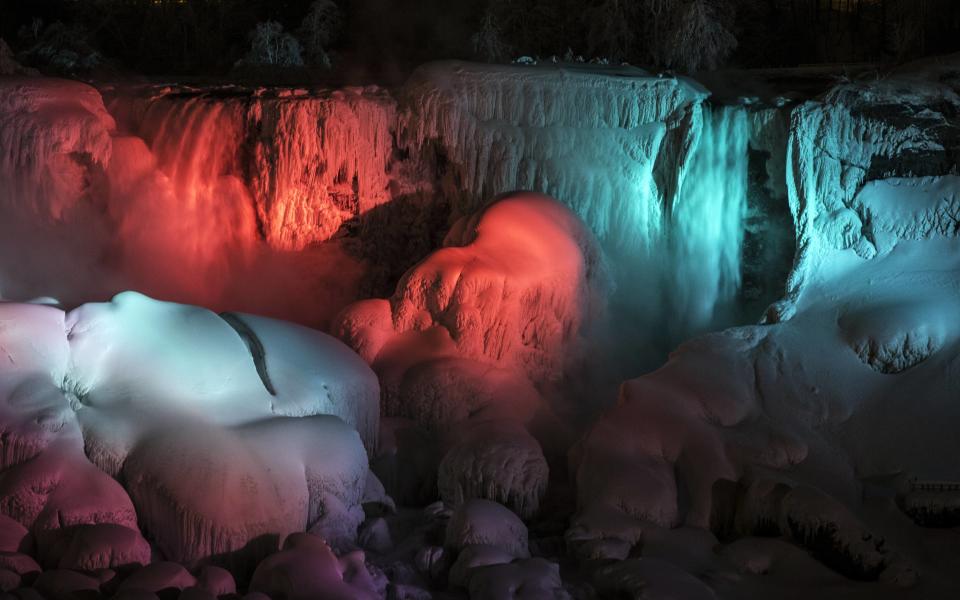 A partially frozen American Falls is seen lit by lights during sub freezing temperatures in Niagara Falls