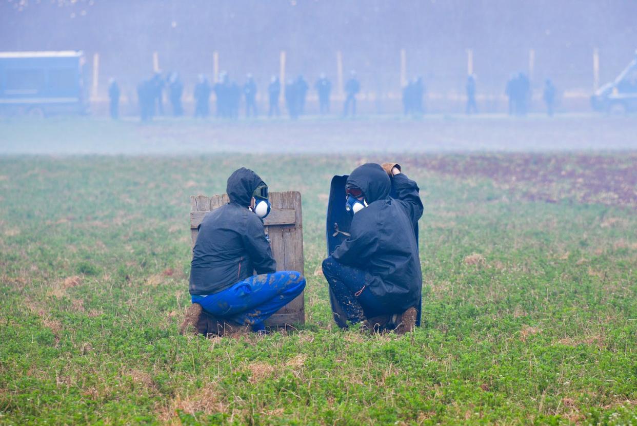 Des manifestants se protègent derrière des boucliers de fortune lors d'affrontements avec des gendarmes à Sainte-Soline, pendant une manifestation contre les méga-bassines, le 25 mars 2023. Pascal Lachenaud / AFP