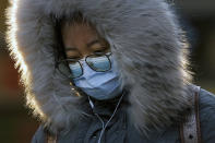 A woman wearing a face mask to help curb the spread of the coronavirus walks on a street in Beijing, Monday, Jan. 4, 2021. Wary of another wave of infections, China is urging tens of millions of migrant workers to stay put during next month's Lunar New Year holiday, usually the world's largest annual human migration. (AP Photo/Andy Wong)