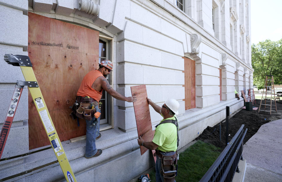 Troy Richardson, left, and Corey Rockweiler with Daniels Construction, board up street level windows near the West Washington entrance to the Capitol in Madison, Wis. Wednesday, June, 24, 2020, the morning after protesters tore down statues of Forward and a Union Civil War colonel. Protesters also assaulted a state senator and damaged the Capitol Tuesday night after the arrest of a Black activist earlier in the day. (Steve Apps/Wisconsin State Journal via AP)