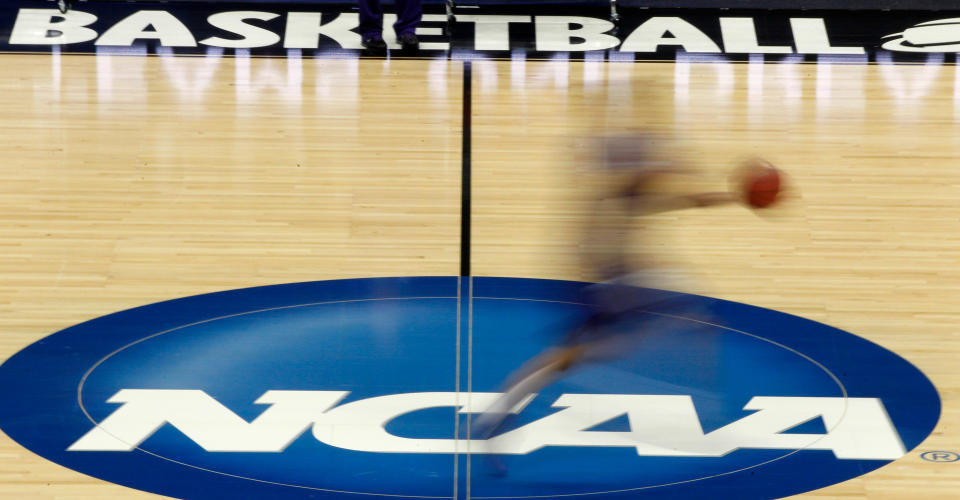 In this file photo, a player runs across the NCAA logo during practice in Pittsburgh before an NCAA tournament game. Major programs are bracing for substantial consequences from the federal corruption trial. (AP)