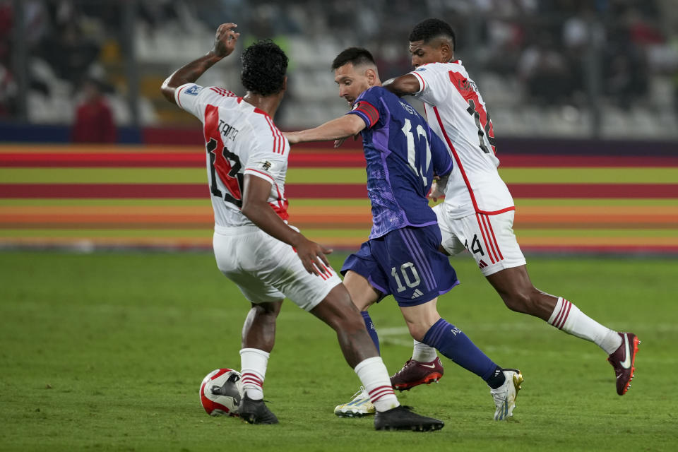 Argentina's Lionel Messi, center, fights for the ball with Peru's Renato Tapia, left, and Wilder Cartagena during a qualifying soccer match for the FIFA World Cup 2026 at the National stadium in Lima, Peru, Tuesday, Oct. 17, 2023.(AP Photo/Guadalupe Pardo)