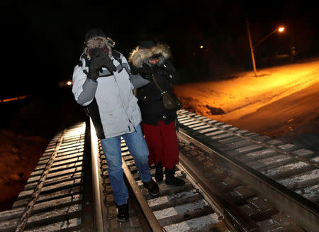 Refugees walk along railway tracks from the United States to enter Canada at Emerson, Manitoba, Canada, February 26, 2017. REUTERS/Lyle Stafford