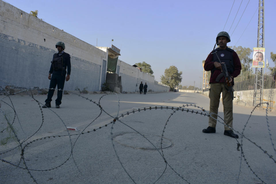 Security officials guard a blocked road leading to a counter-terrorism center after security forces starting to clear the compound seized earlier by Pakistani Taliban militants in Bannu, a northern district in the Pakistan's Khyber Pakhtunkhwa province, Tuesday, Dec. 20, 2022. Pakistan's special forces on Tuesday stormed the counter-terrorism center to free several security officials who were taken hostage earlier this week by a group of detained Pakistani Taliban militants, security officials said. (AP Photo/Muhammad Hasib)