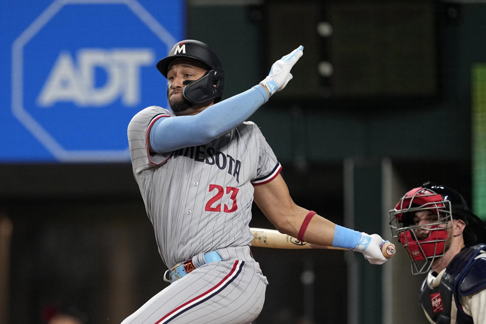 Minnesota Twins' Royce Lewis (23) follows through on an infield single as Texas Rangers' Jonah Heim, right, looks on in the fourth inning of a baseball game, Friday, Sept. 1, 2023, in Arlington, Texas. (AP Photo/Tony Gutierrez)