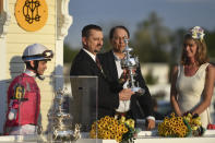 Rombauer trainer Michael McCarthy, second from left, holds the trophy as jockey Flavien Prat, left, and horse owners John Fradkin and Diane Fradkin look on after winning the 145th Preakness Stakes horse race at Pimlico Race Course, Saturday, May 15, 2021, in Baltimore. (AP Photo/Will Newton)