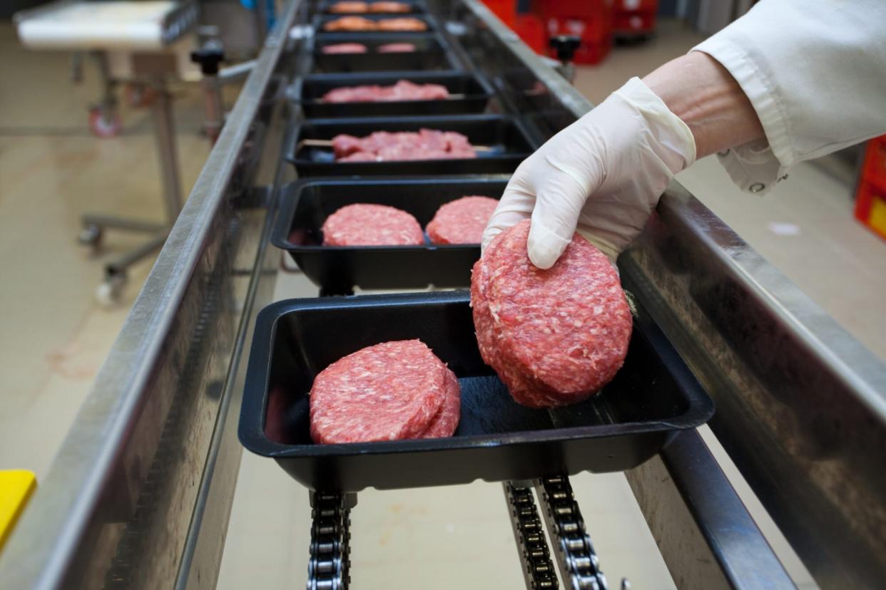 a person's hand is shown packing a beef patty in a black container