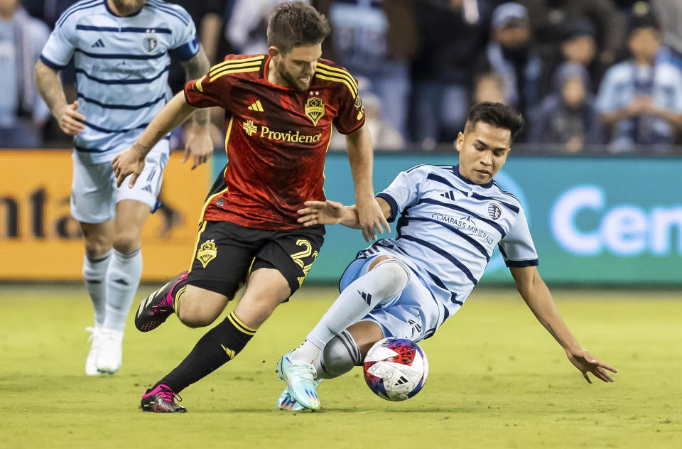 Seattle Sounders midfielder Kelyn Rowe (22) attempts to take the ball from Sporting Kansas City midfielder Felipe Hernandez, right, during the second half of an MLS soccer match on Saturday, March 25, 2023, in Kansas City, Kan. (AP Photo/Nick Tre. Smith)