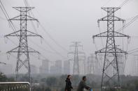 People walk past electricity pylons in Shenyang