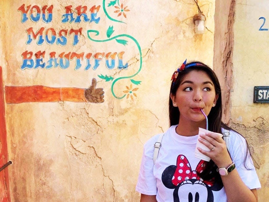 saira drinking a drink in animal kingdom in front of you are most beautiful sign