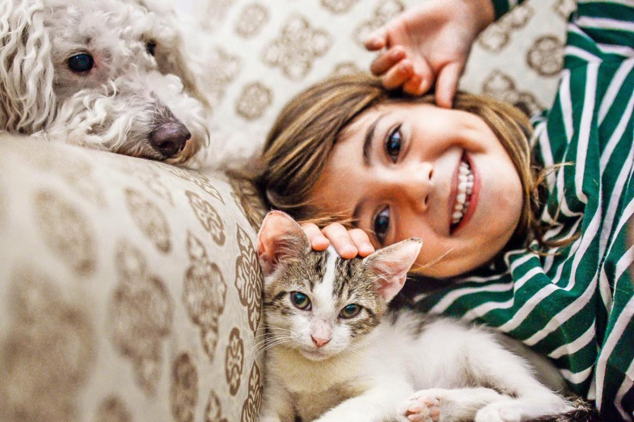 girl with cat at dog on couch; pet holidays