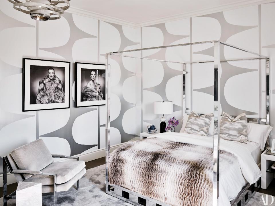 A vintage Milo Baughman four-poster and chair add to the monochrome aesthetic of a guest bedroom. On bed, Frette linens; vintage photographs of Kris Jenner.