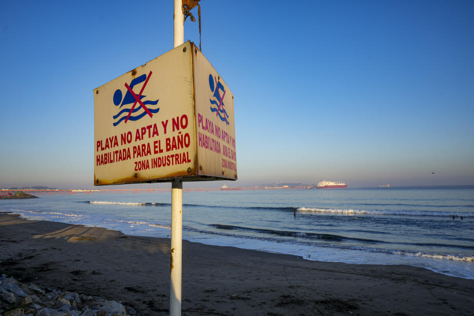 Un cartel avisa a las personas de la prohibición de bañarse en la playa cerca de la Fundición Ventanas, de la empresa estatal Codelco, en su primer día de cierre en la bahía de Quintero en Puchuncavi, Chile, el miércoles 31 de mayo de 2023. El presidente chileno, Gabriel Boric, anunció en junio de 2022 el cierre gradual de la mayor productora mundial de cobre con el fin de reducir los episodios de contaminación ambiental que afectan a las comunas costeras cercanas al horno de fundición. (AP Foto/Esteban Félix)